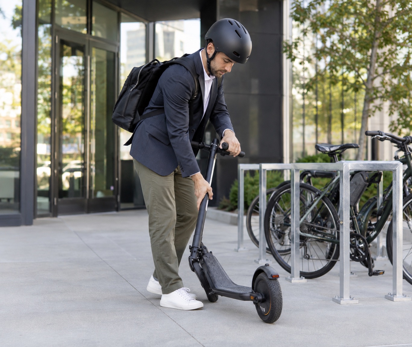 Commuter folding an electric scooter beside an office bike storage area